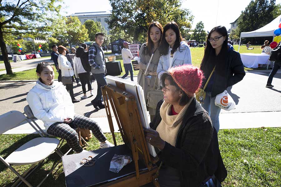 students standing around a women painting  a photo