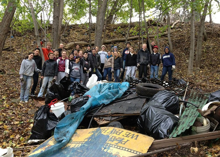 a large group of students on a hillside collecting trash and garbage