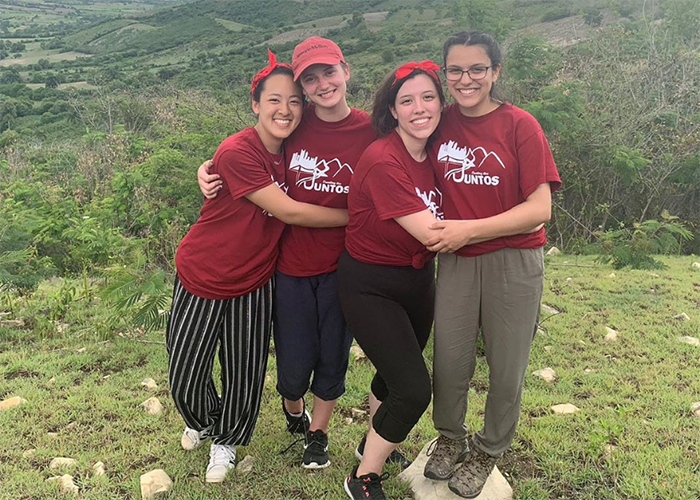 four students smiling on top of a mountain in the deep countryside