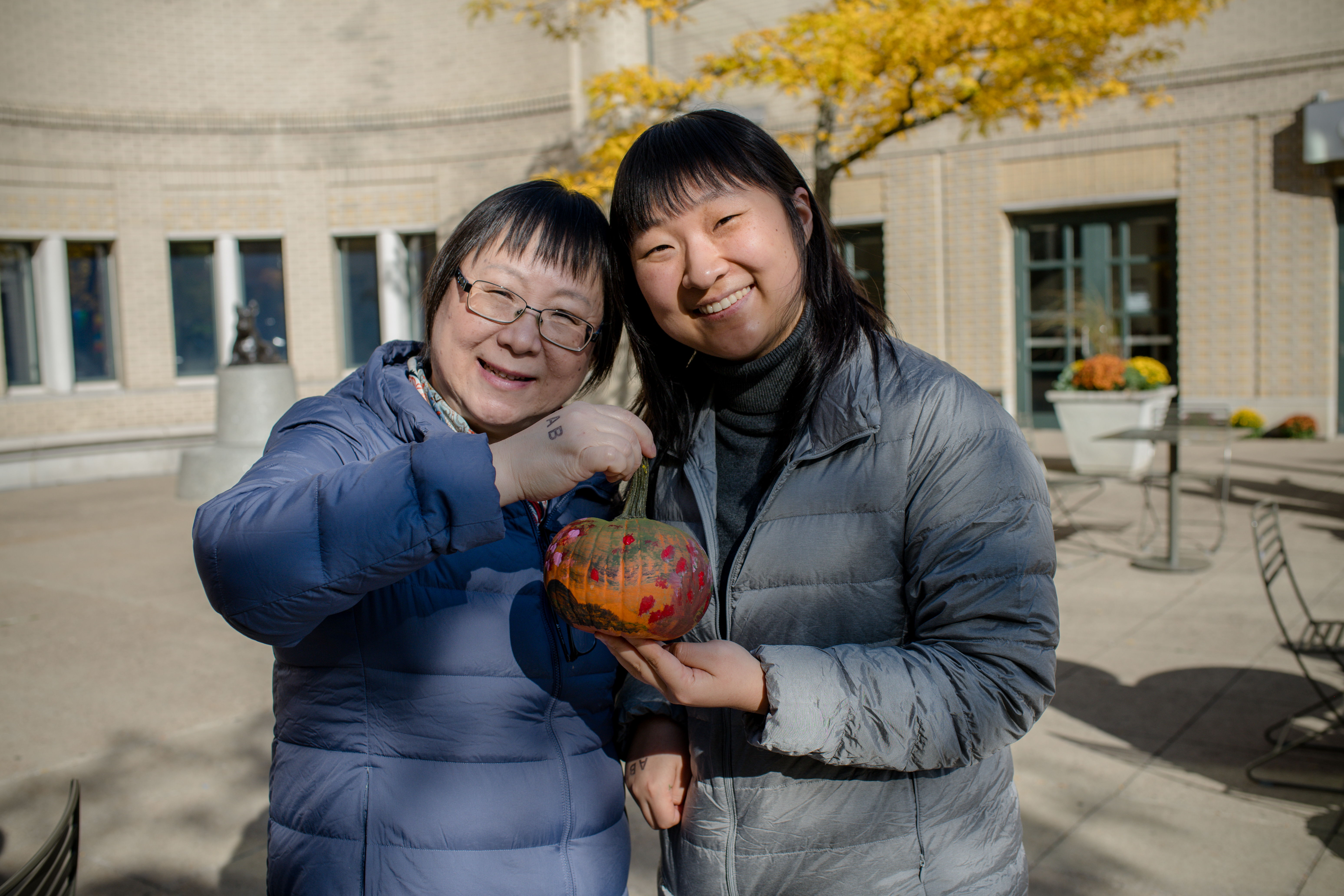 photo of two women posing with a painted pumpkin