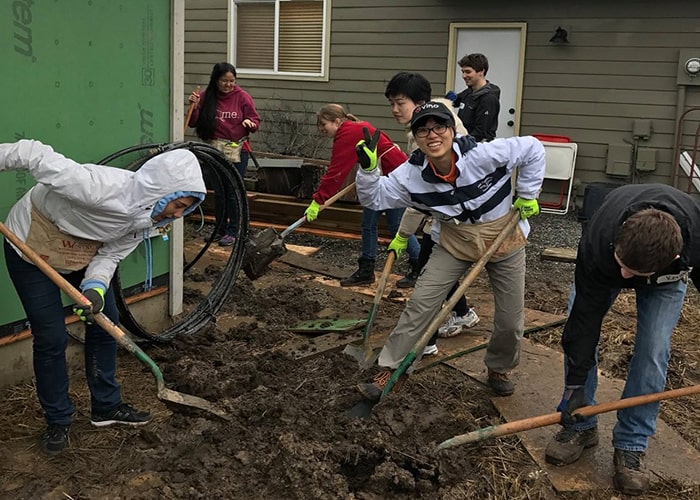 Students building and digging in front of Habit for Humanity project