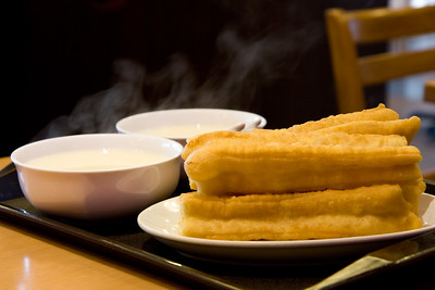 an image of a fried food with steaming bowls in the background