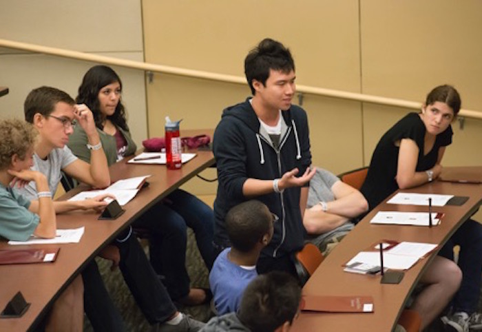 student talking to peers in a lecture hall 