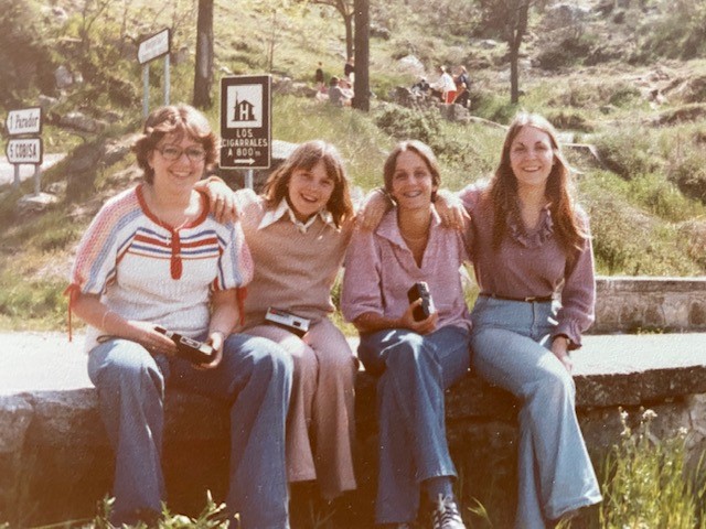 Linda Gentile poses on a wall in Spain with her high school classmates. It is the '70s and they are dressed like it's the '70s.