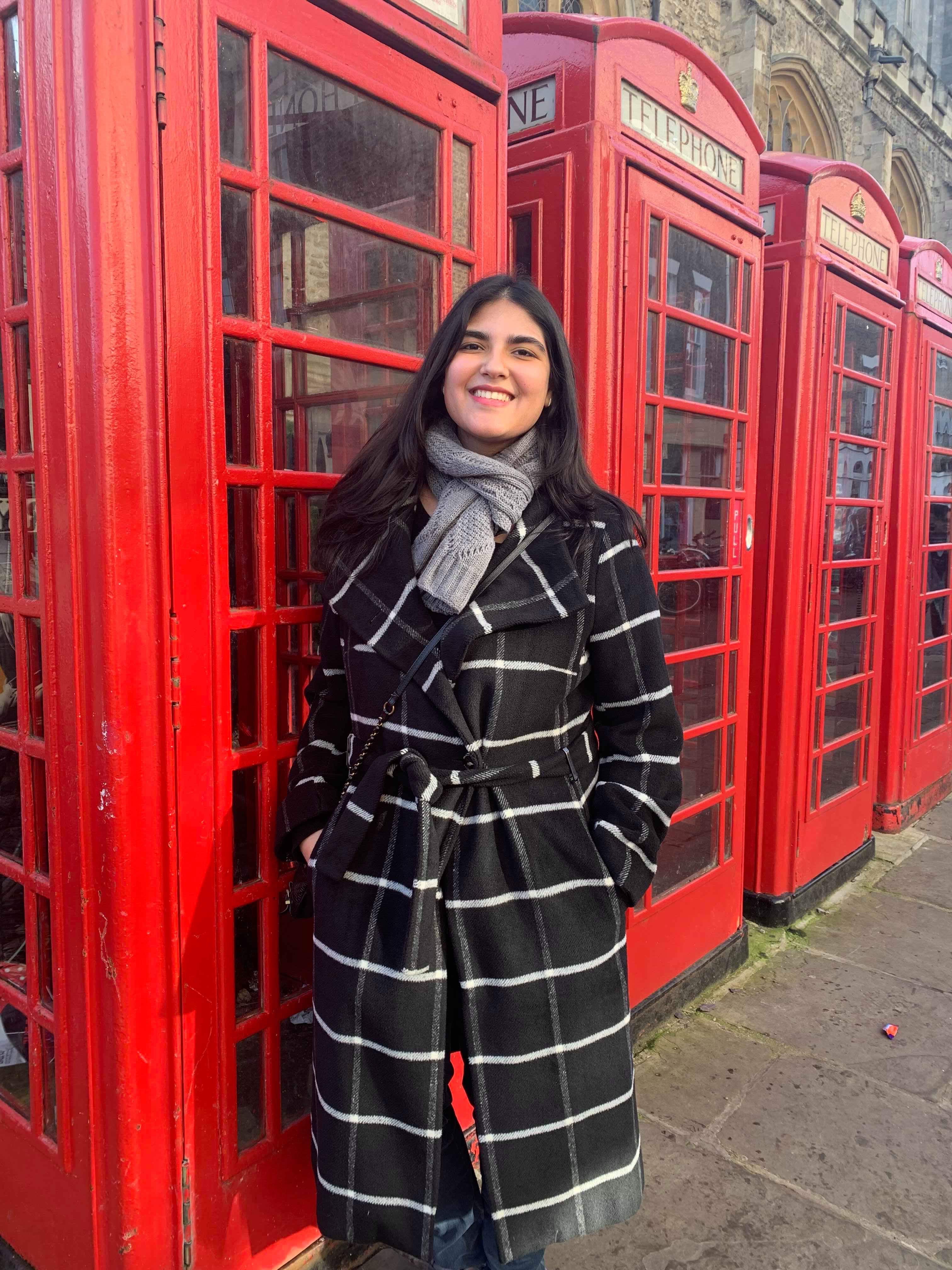 Smriti in front of a row of red phonebooths in London