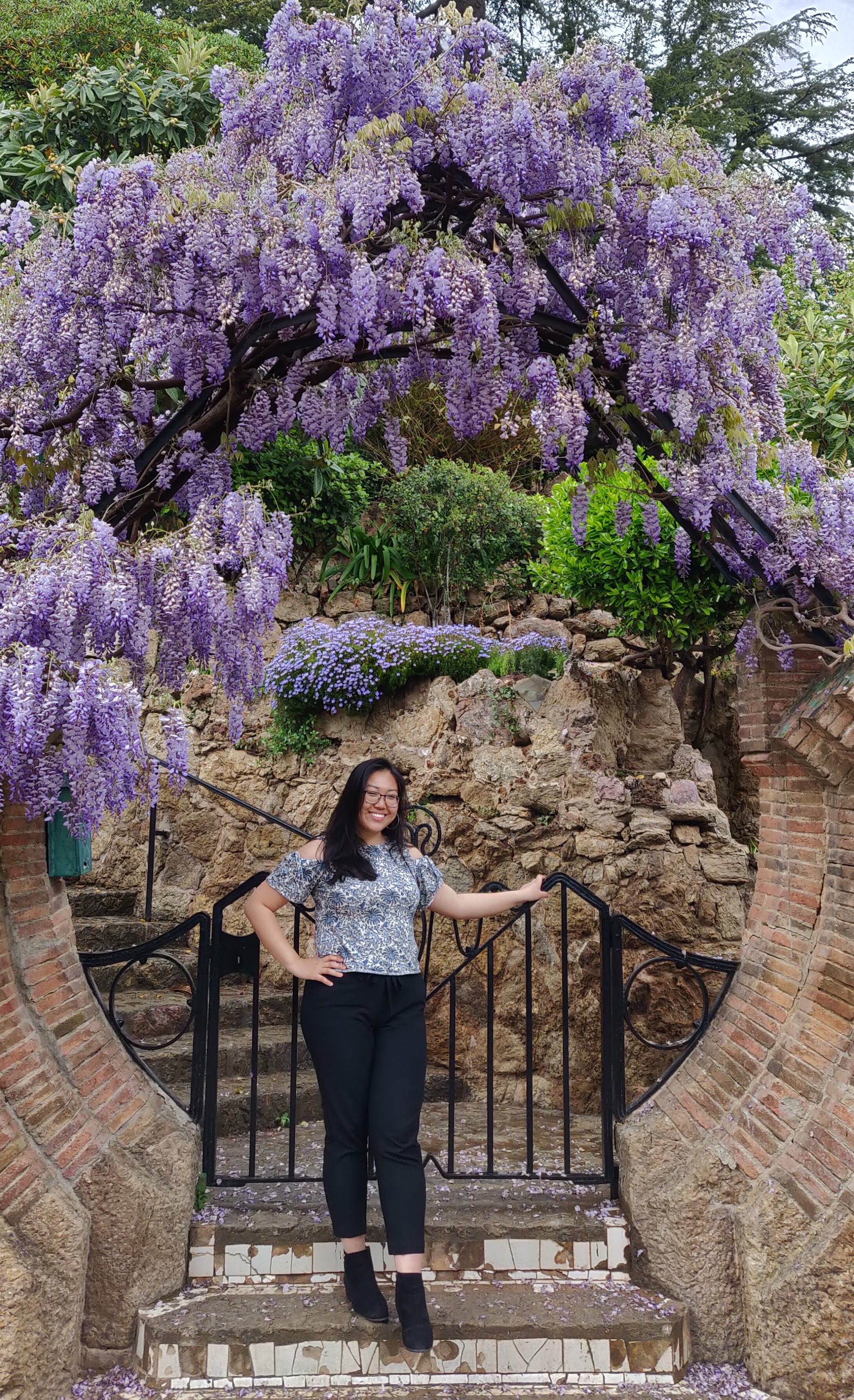 Lisa Han posing under a circular archway covered in lilacs