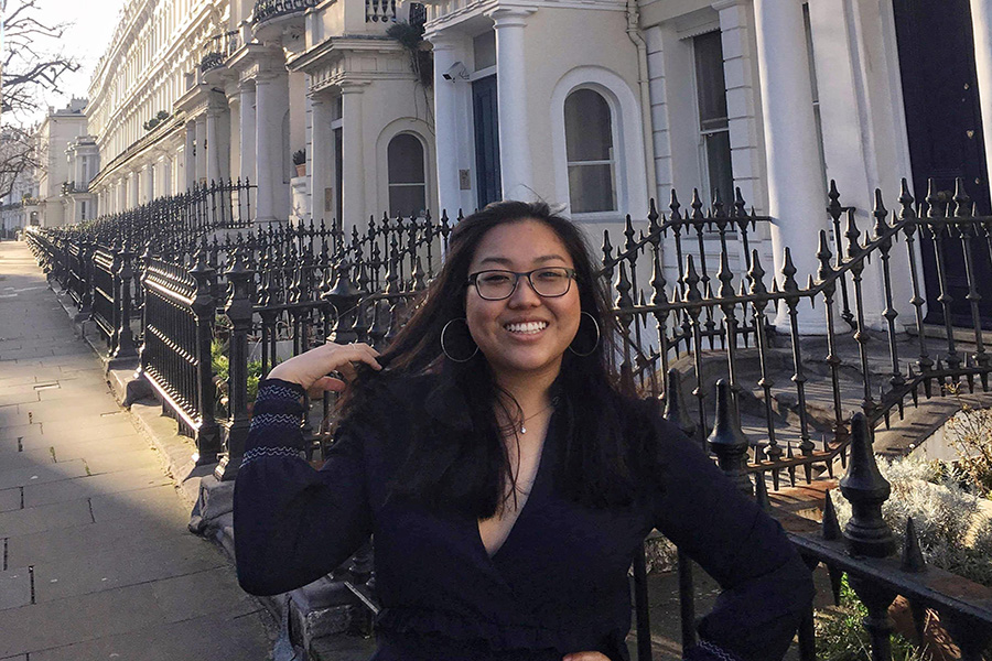 Lisa Han flipping her hair and laughing on a street lined in fancy row houses.