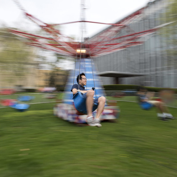 Action shot of a man riding the swings at a carnival.