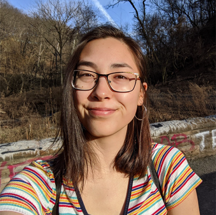 Jenna Stanislaw takes an outdoor selfie in front of railroad tracks.