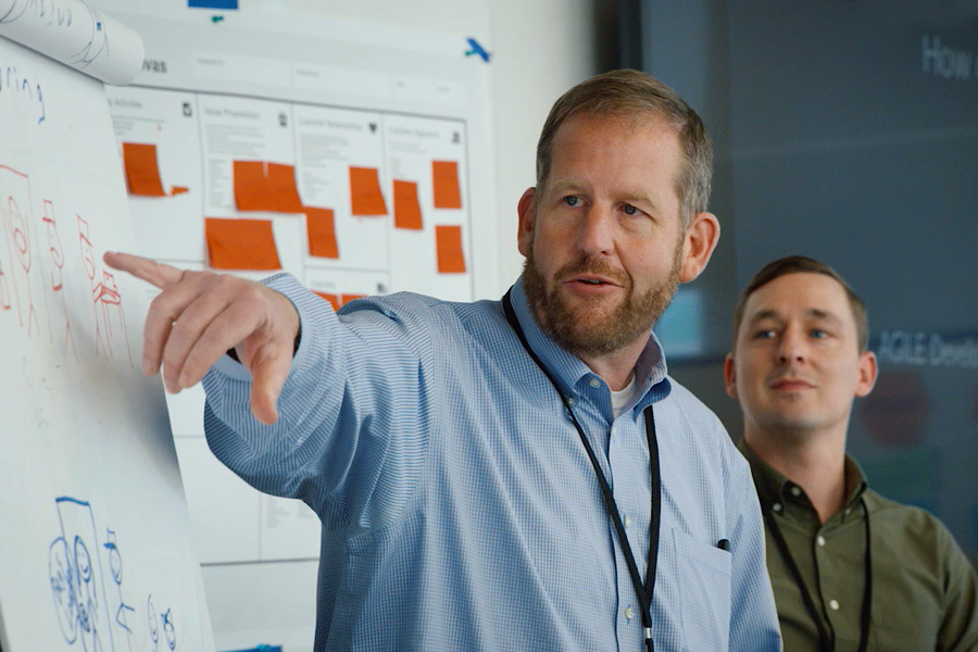 photo of two males discussion ideas written on post it notes and hung on wall