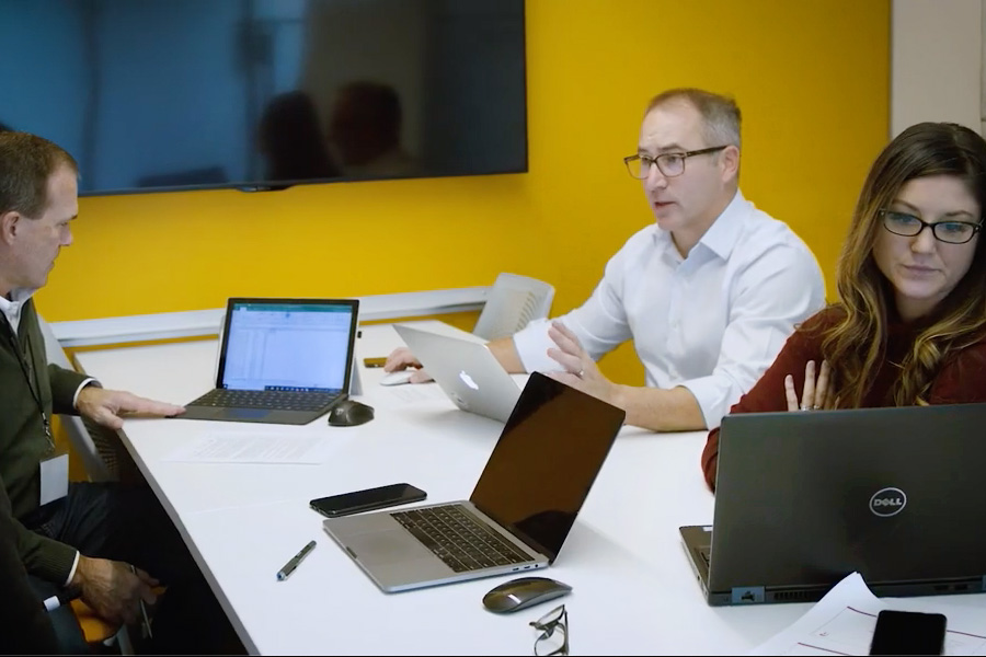 people at conference table working on laptops and talking
