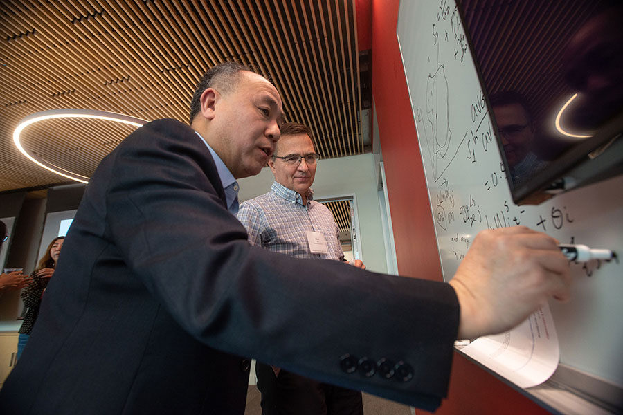 Two men working at a whiteboard and discussing