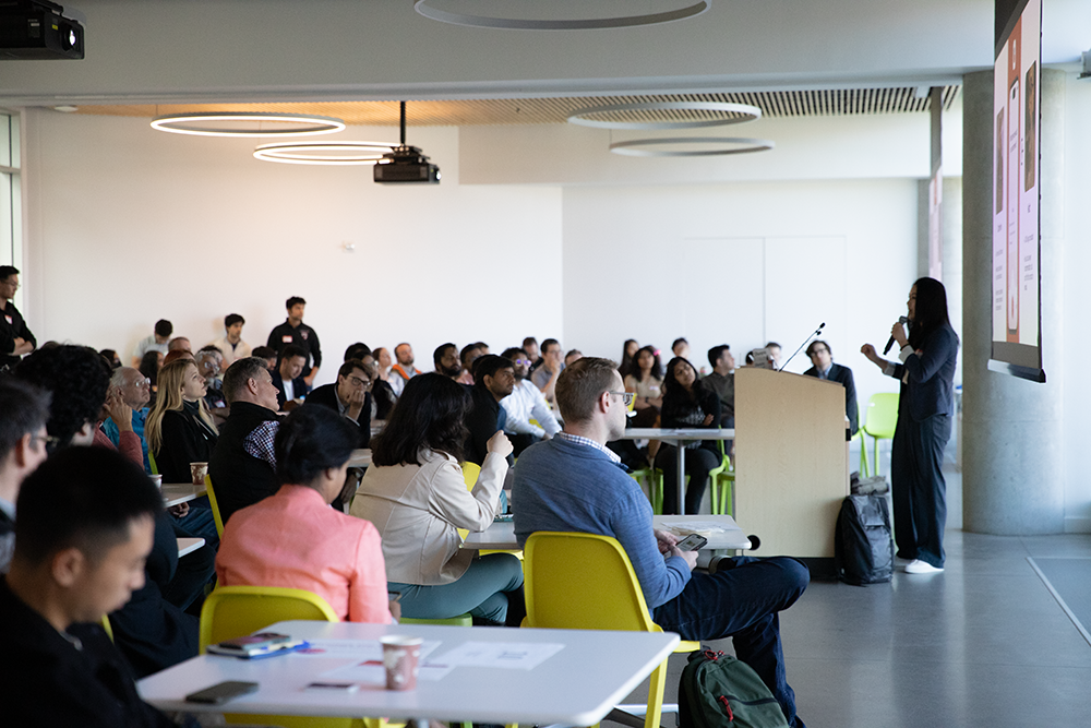 A photo of a presenter speaking to a room of people