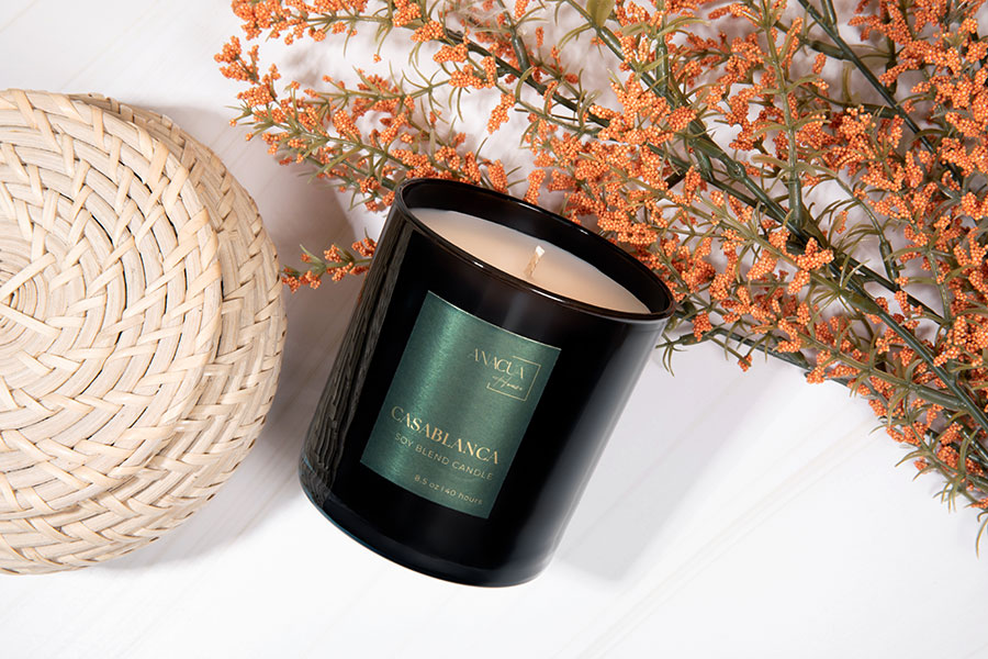 Anacua House signature candle on a bed of orange berry branches.