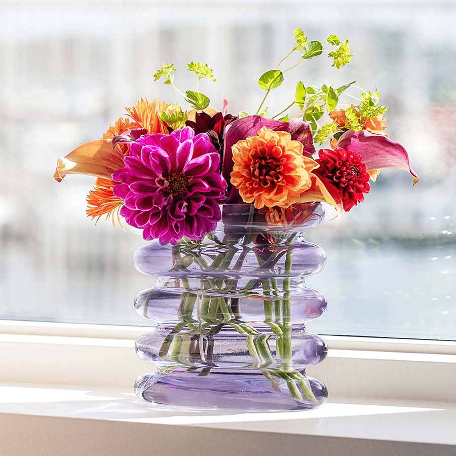 Purple Anacua House vase with pink and orange fall dahlias against white background.