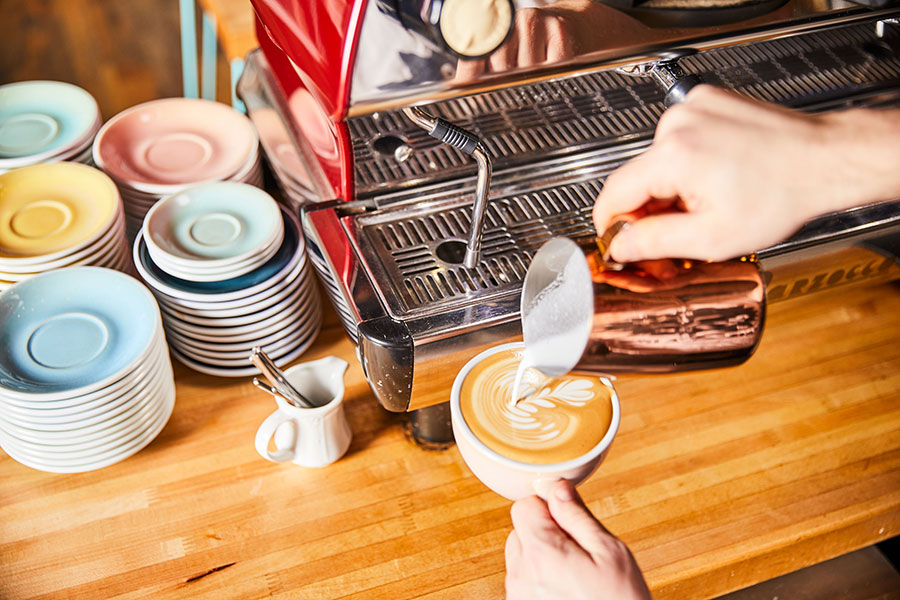 Hand pouring hand-crafted coffee latte art.