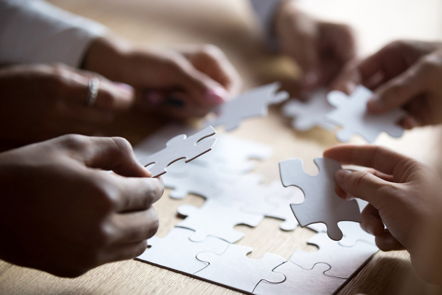 Hands holding puzzle pieces assembling a puzzle representing the concept of teamwork