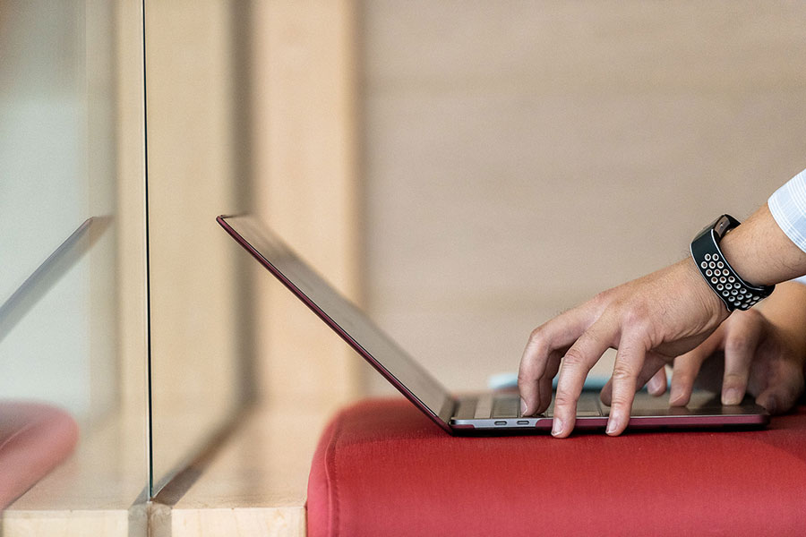 male hands typing on laptop with red background