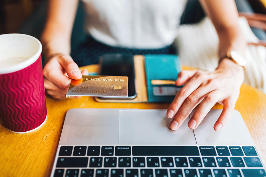 Female hands at a laptop and holding a credit card