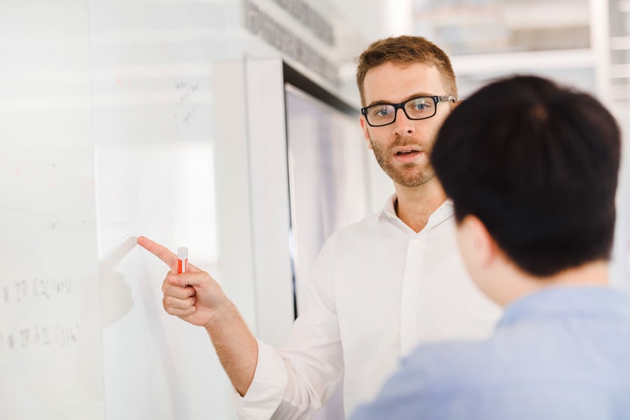 photo of two Ph.D. students using white board wall to brainstorm