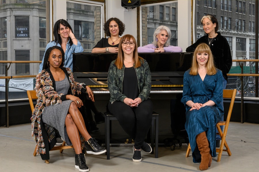 Photo of prominent women who work on Broadway, posed around a piano.