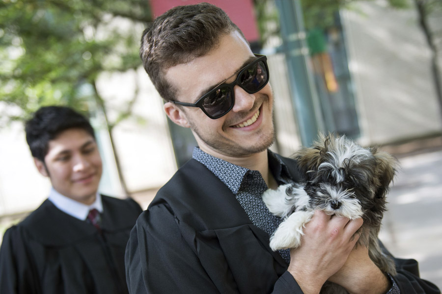 A graduate holding a puppy.