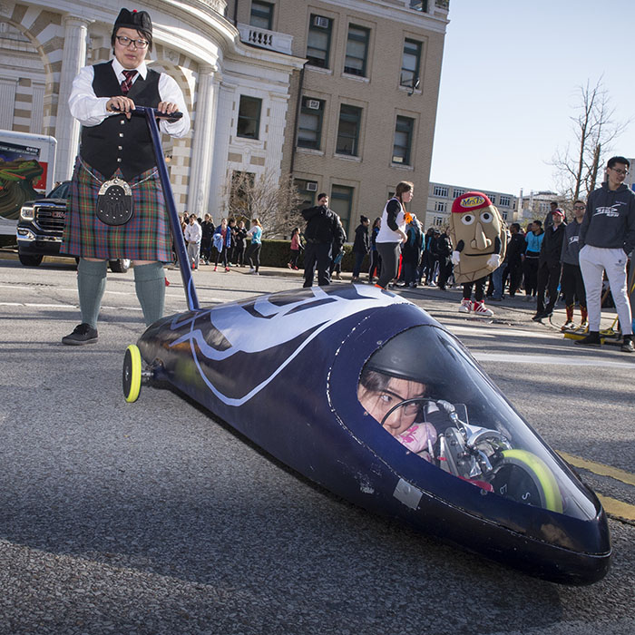 Student in a buggy being pushed by another person in a kilt.