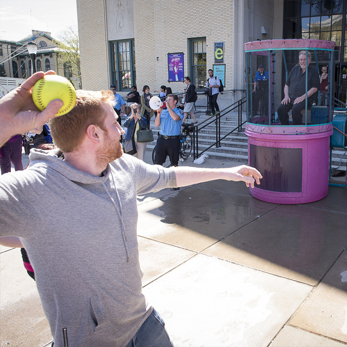Man throwing ball at dunking booth.