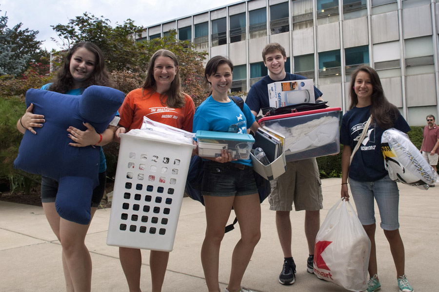 Students holding belongings on move in day.