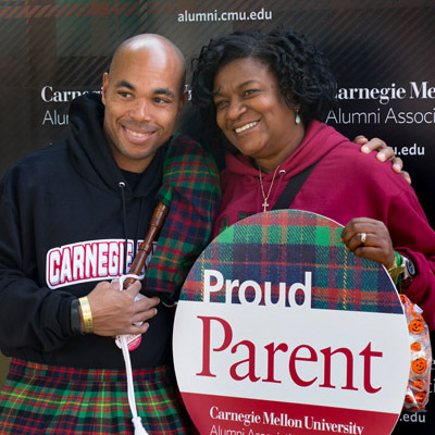 Student and mother holding proud parent sign.