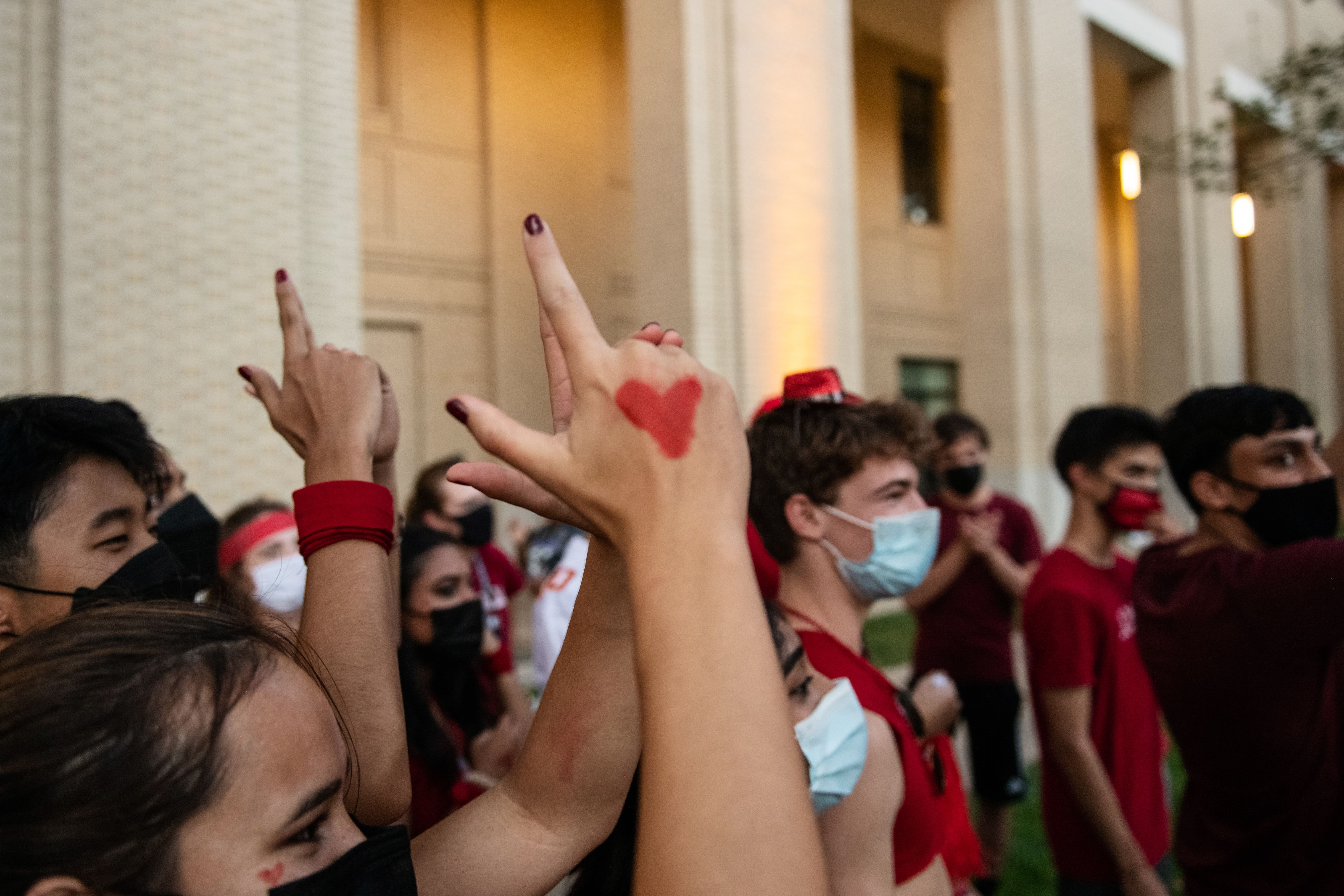 CMU students chant in a group for House Wars with a close up on a hand- painted heart