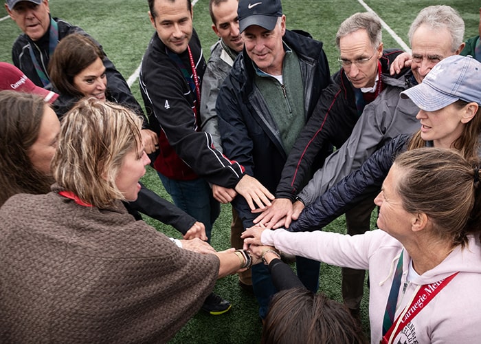 Coaches put their hands together in a circle for Homecoming