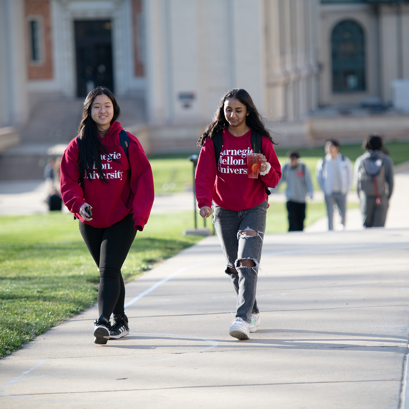 two girls wearing red CMU hoodies walking on campus